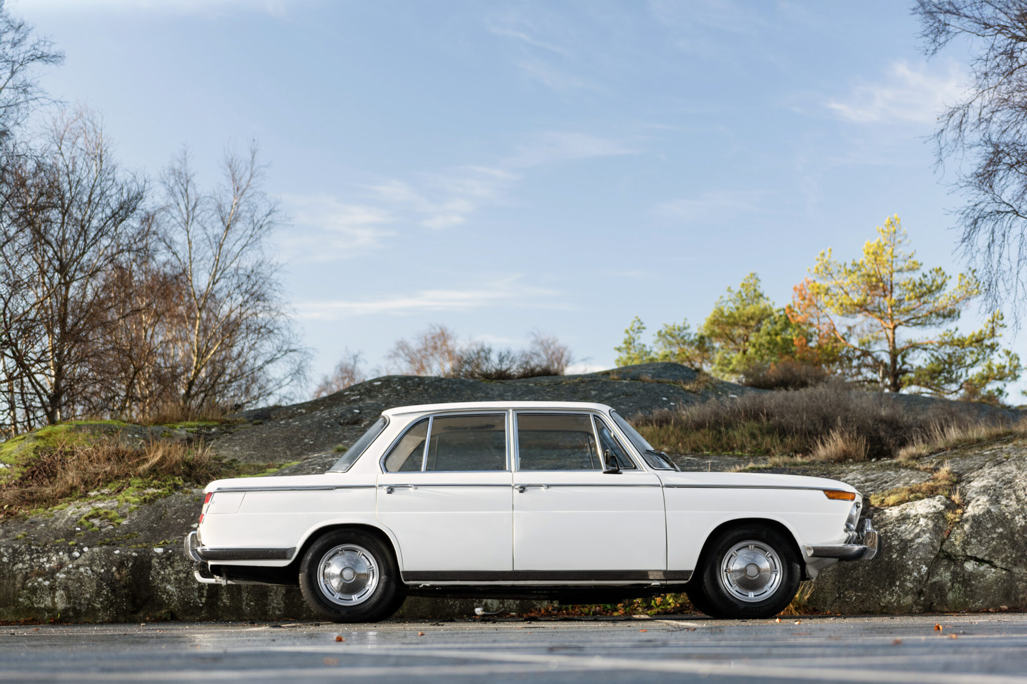 BMW 1800 Neue Klasse från 1964 i klassisk vit färg, fotograferad i höstlandskap – exklusivt presenterad av Runbox.se.